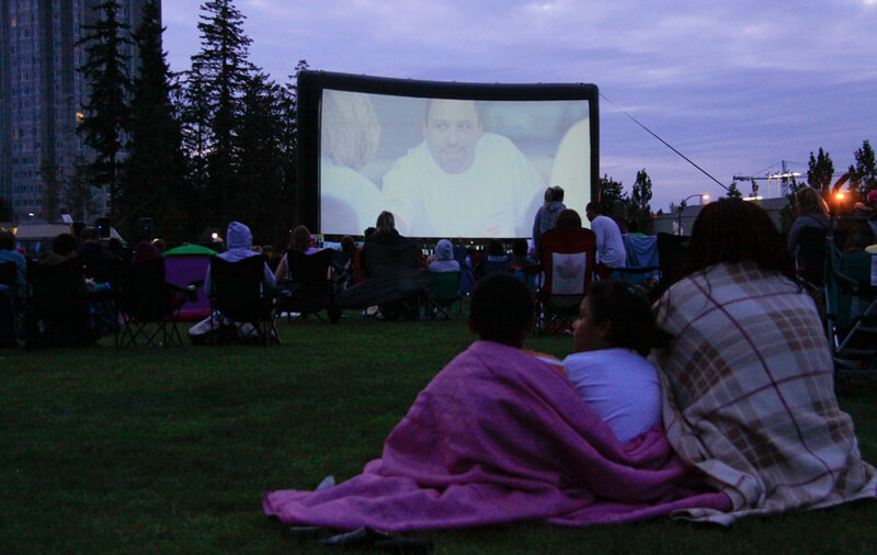 group of people watching a movie at an outdoor theatre