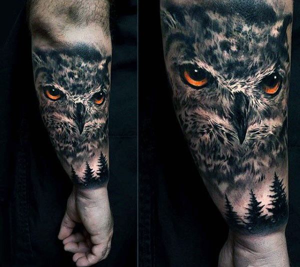 owl face above pine trees men's lower arm tattoo