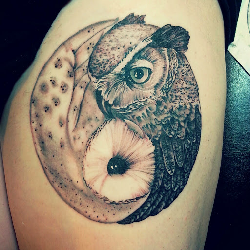 owl nestled around flower men's arm tattoo