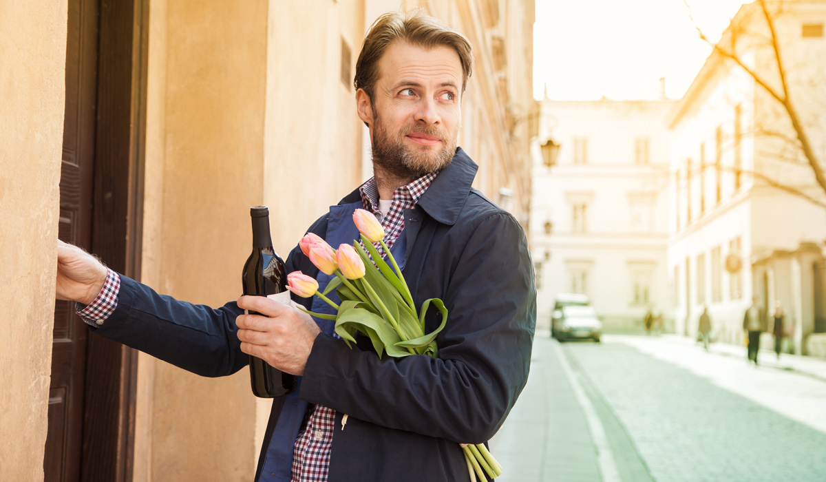handsome gentleman holding flowers and wine